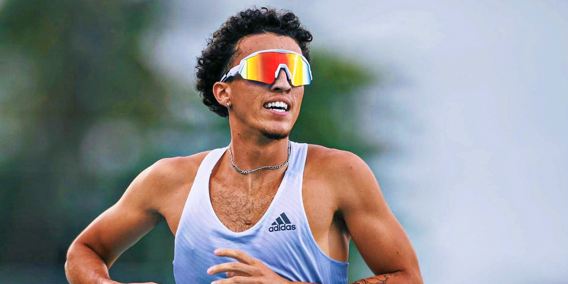 Man running in a track uniform with sunglasses