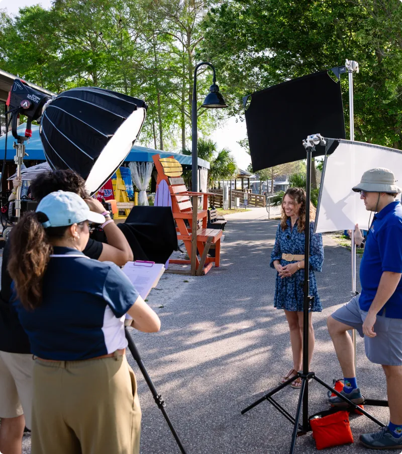 Film crew recording an individual on a park path.